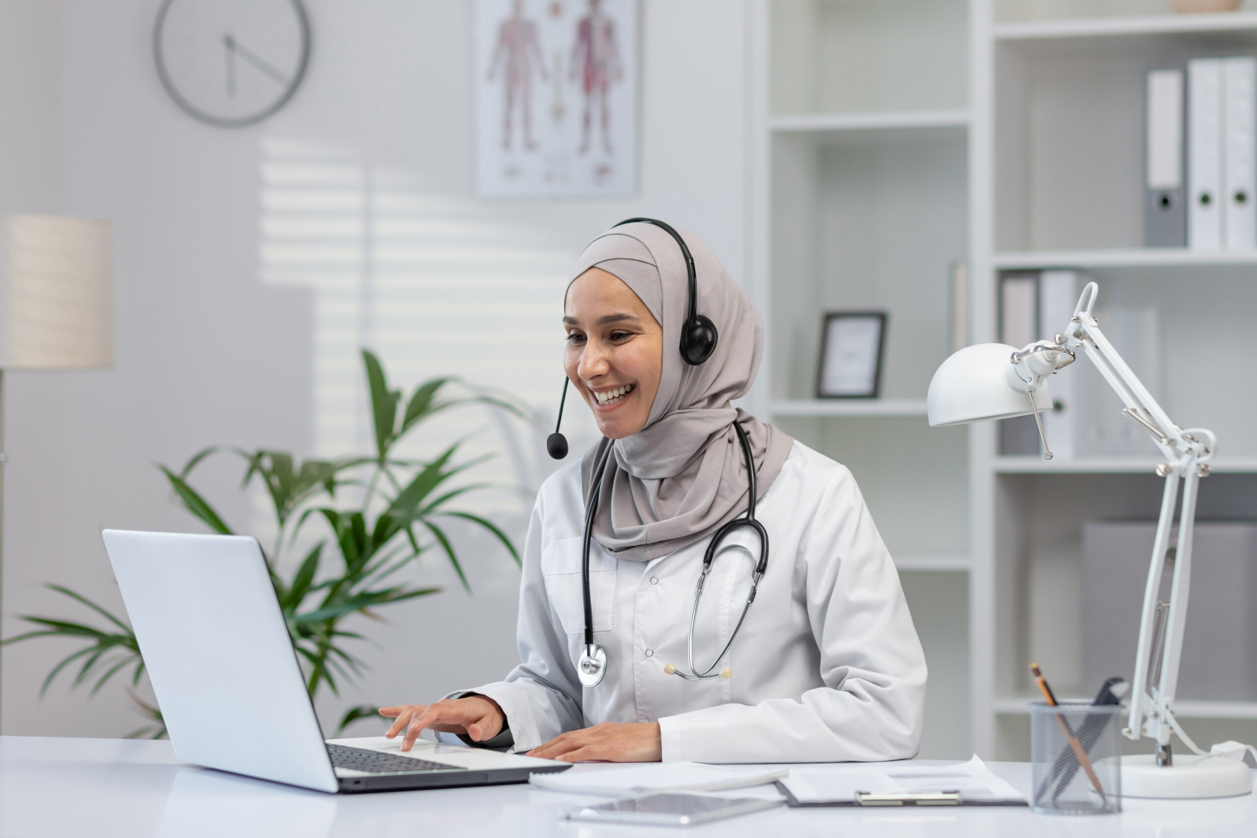 Smiling female doctor in hijab consulting online from office